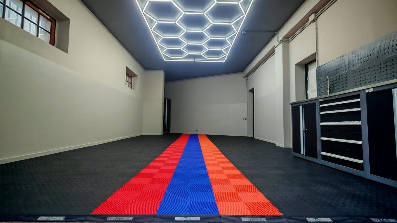 DOPO Empty room with a patterned floor featuring red and blue stripes and hexagonal ceiling lights.